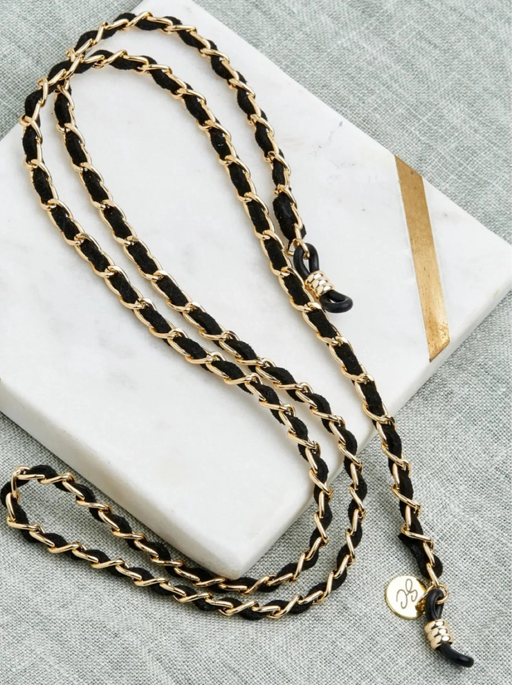 Black and gold chain necklace on a white surface with a gray background